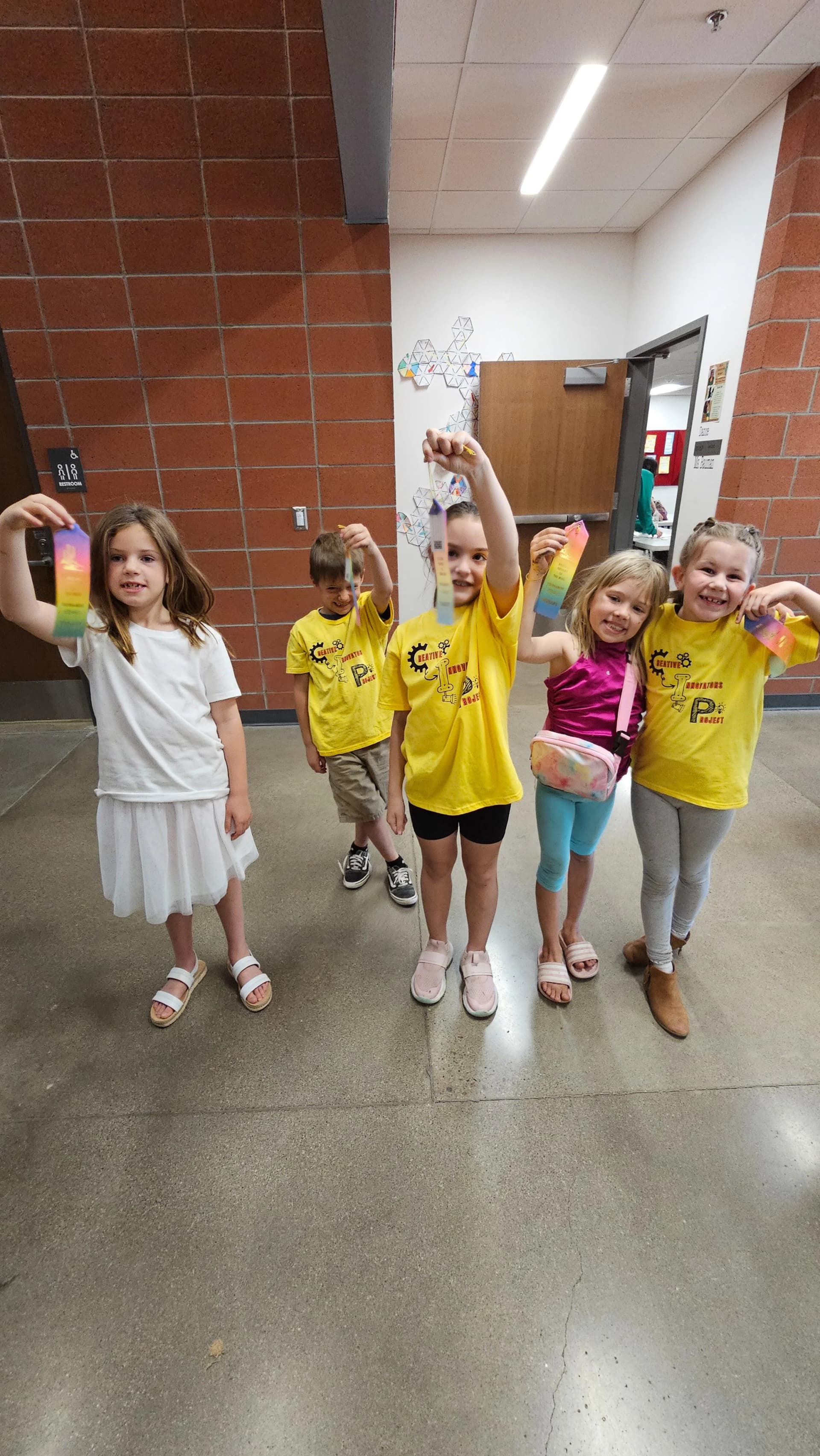 Five CIP students holding rainbow ribbons in a hallway