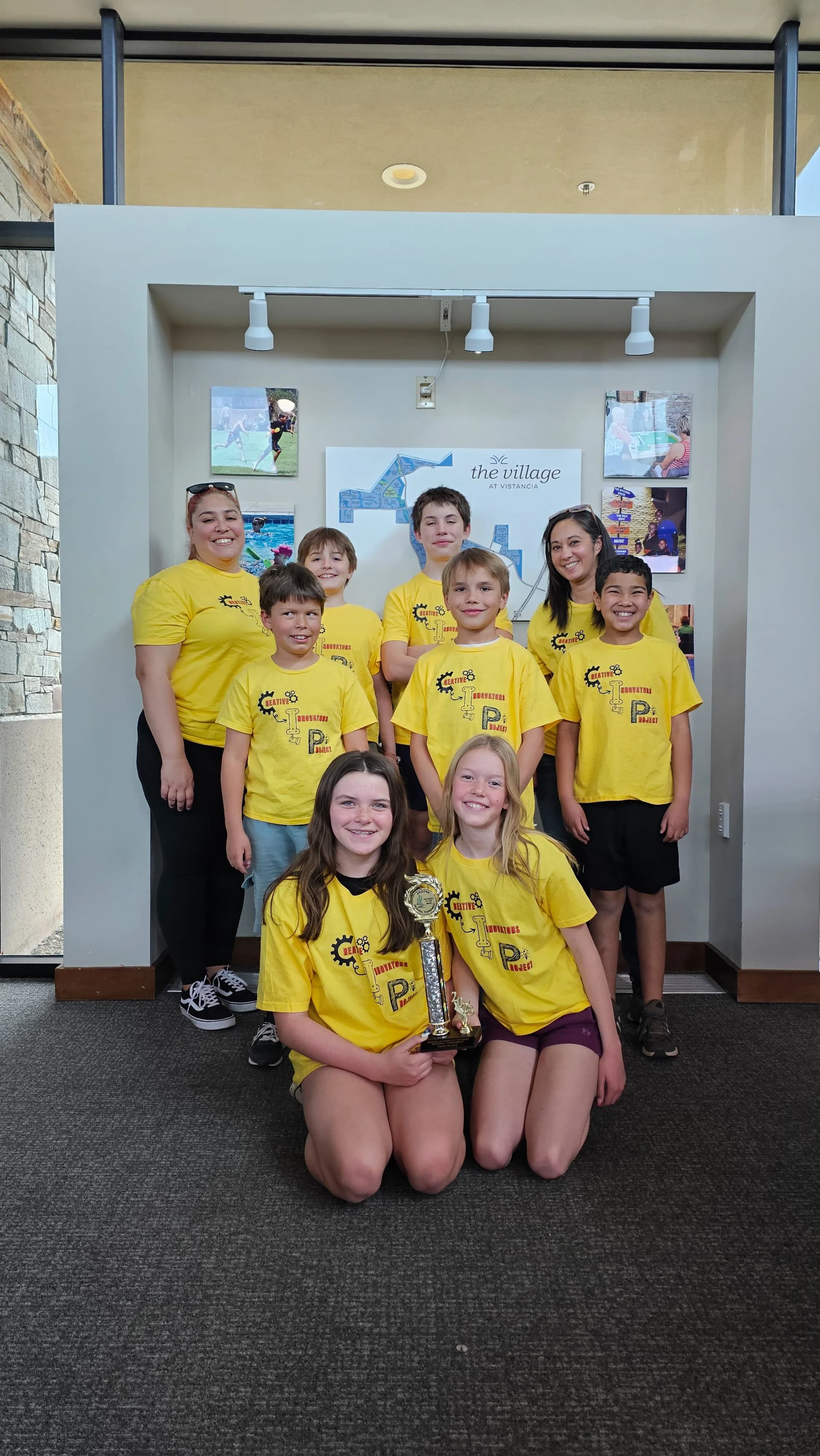 CIP team in matching yellow shirts posing with a trophy