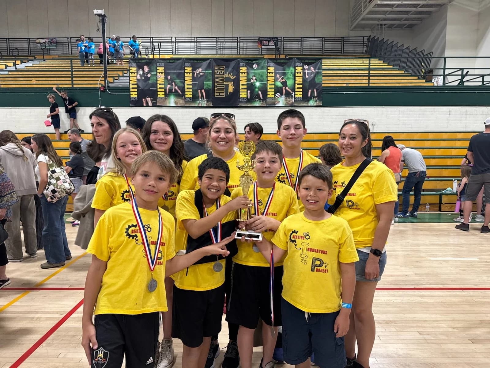 CIP students in yellow team shirts celebrating with medals and a trophy at a tournament